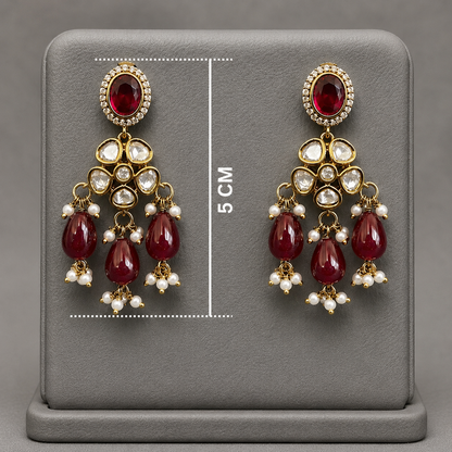 A pair of gold-plated dangle earrings with red gemstones and clear stones, displayed on a gray stand with a 5 cm height measurement overlay.