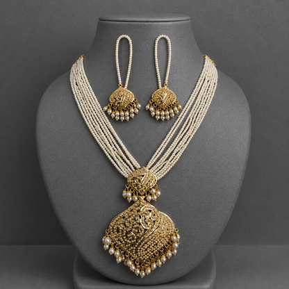 An ornate Indian traditional jewelry set featuring a multi-strand pearl necklace with a large gold filigree pendant and matching gold and pearl earrings, displayed on a gray mannequin bust.