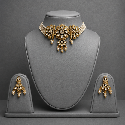 Gold-toned traditional Indian jewelry set featuring a choker necklace and matching earrings, displayed on a gray jewelry bust and stand against a dark gray background.