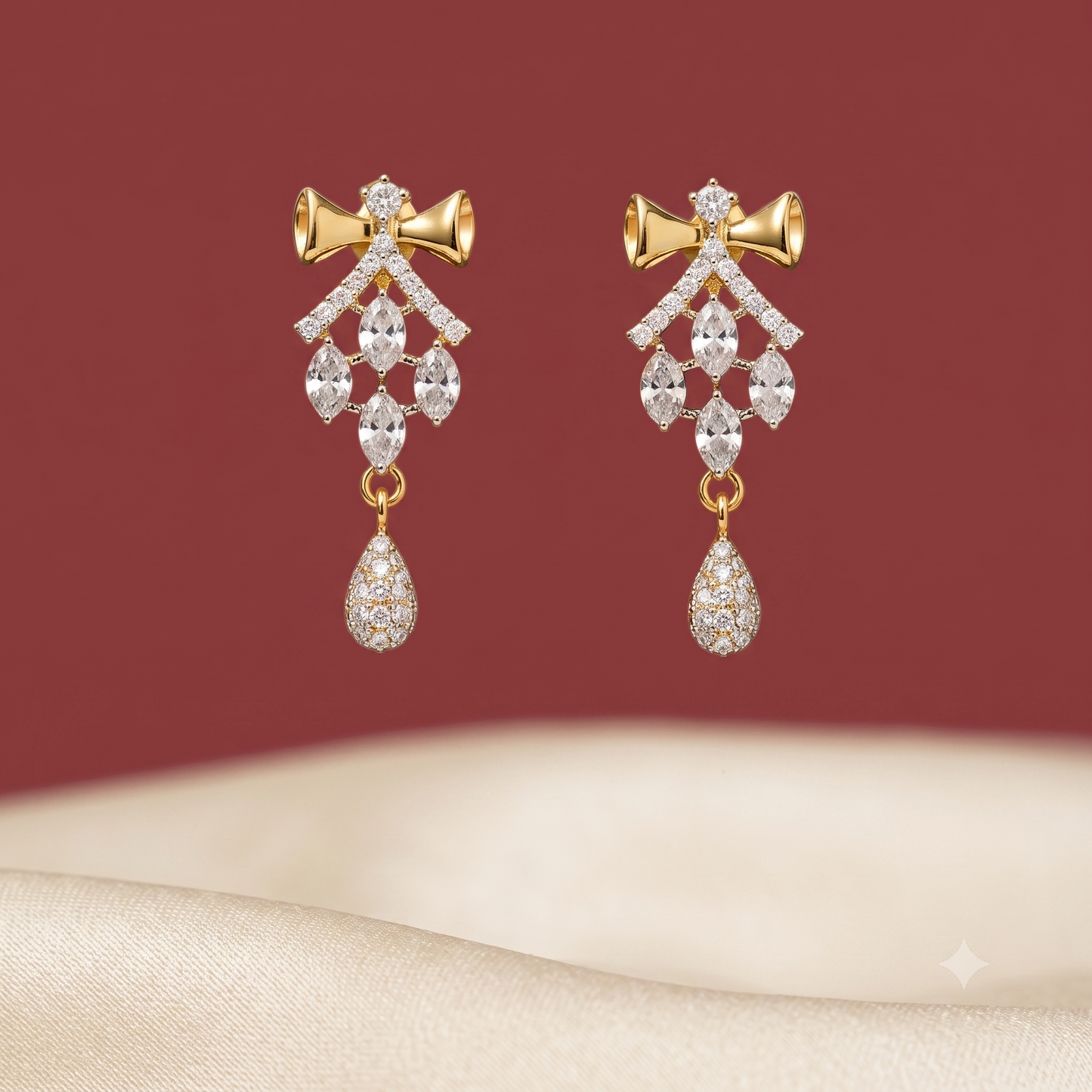 Pair of gold-tone American Diamond drop earrings featuring a bow design.