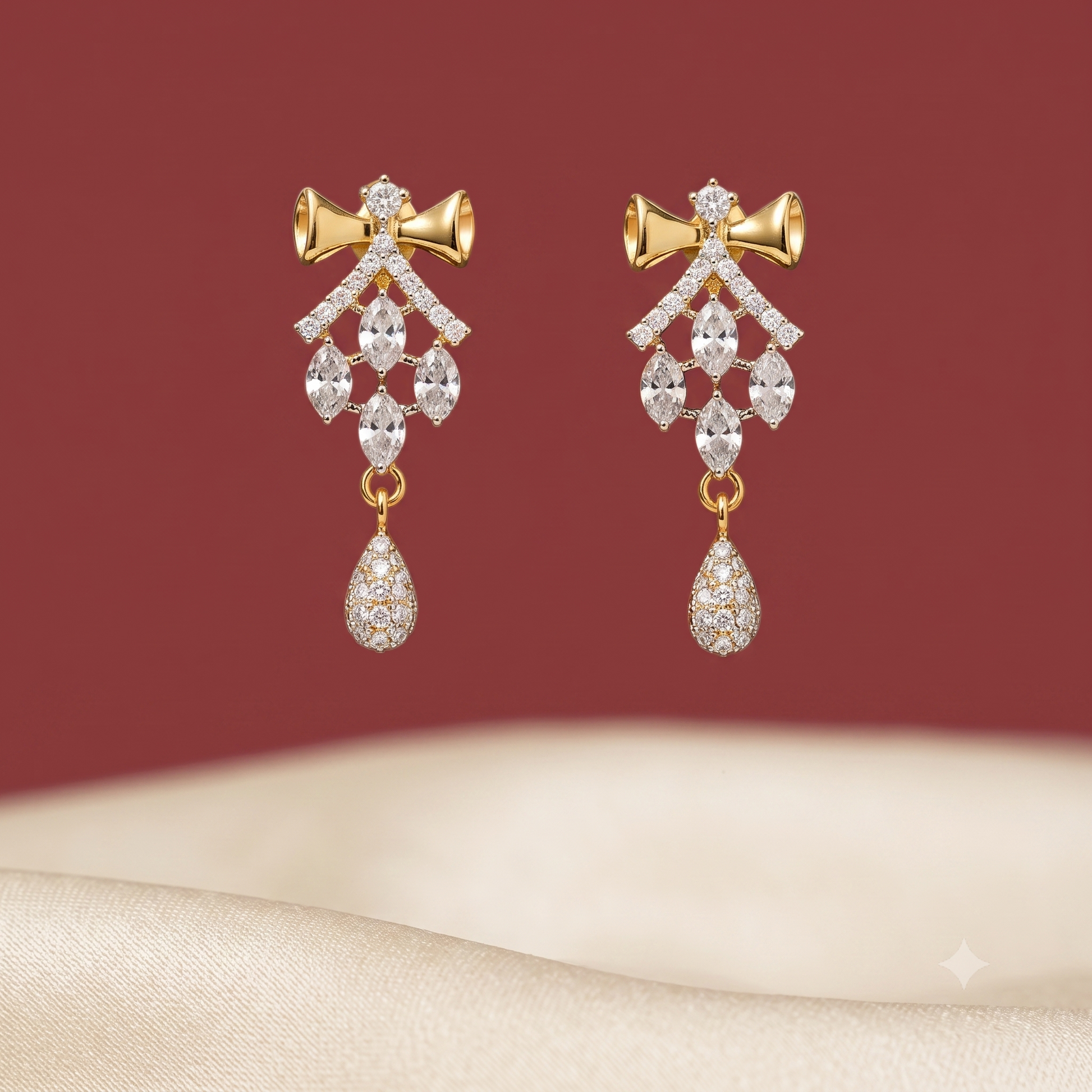 Pair of gold-tone American Diamond drop earrings featuring a bow design.