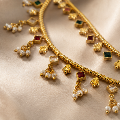 Extreme close-up of the gold-tone earring chain highlighting the intricate links, diamond-shaped color stones, and delicate pearl drops.