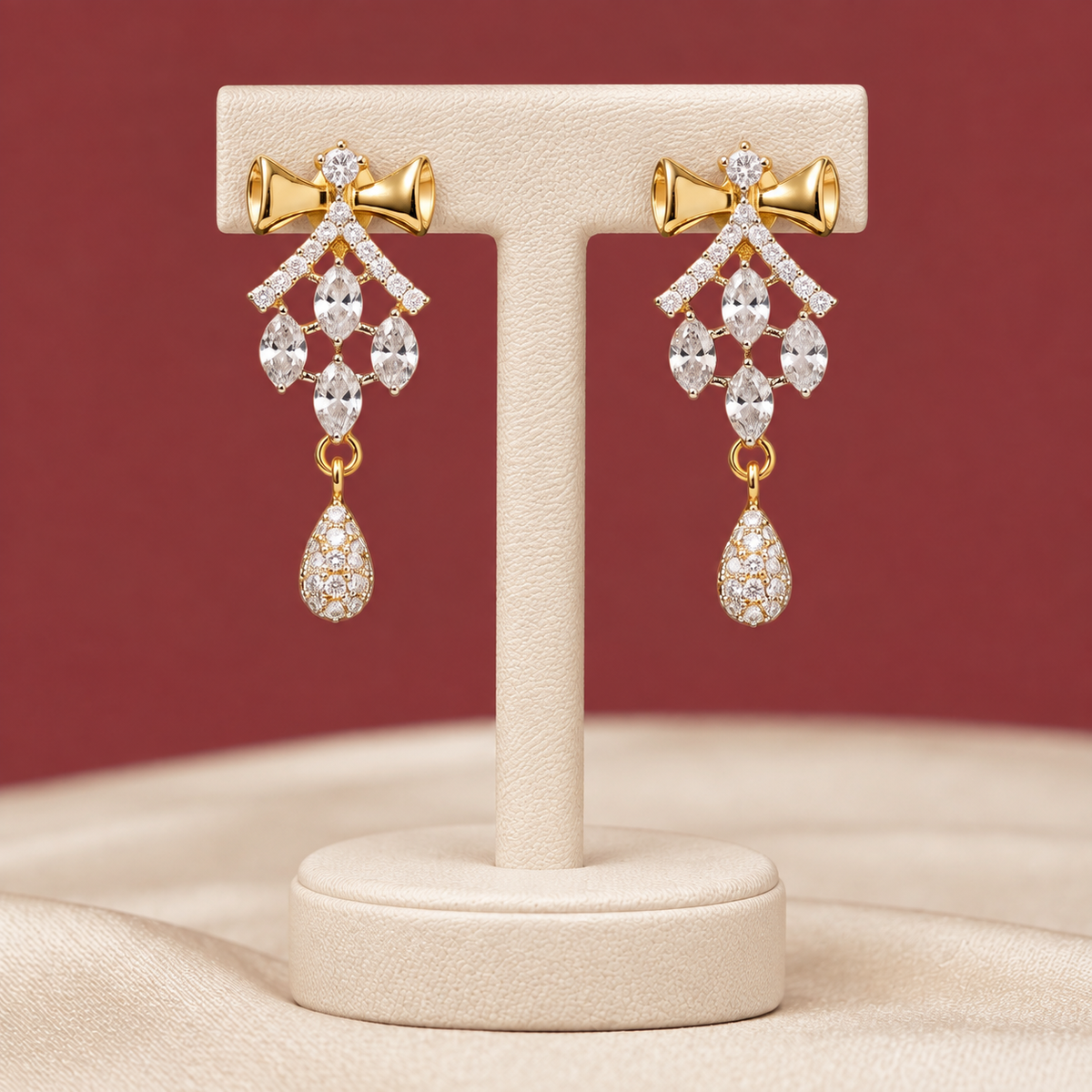Pair of antique gold-tone drop earrings detailed with royal crimson gemstones and hanging pearls on textured crimson velvet.