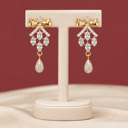 Pair of antique gold-tone drop earrings detailed with royal crimson gemstones and hanging pearls on textured crimson velvet.
